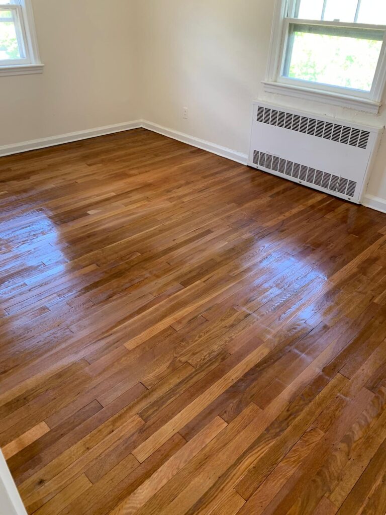 Freshly installed polished hardwood flooring in a residential living room
