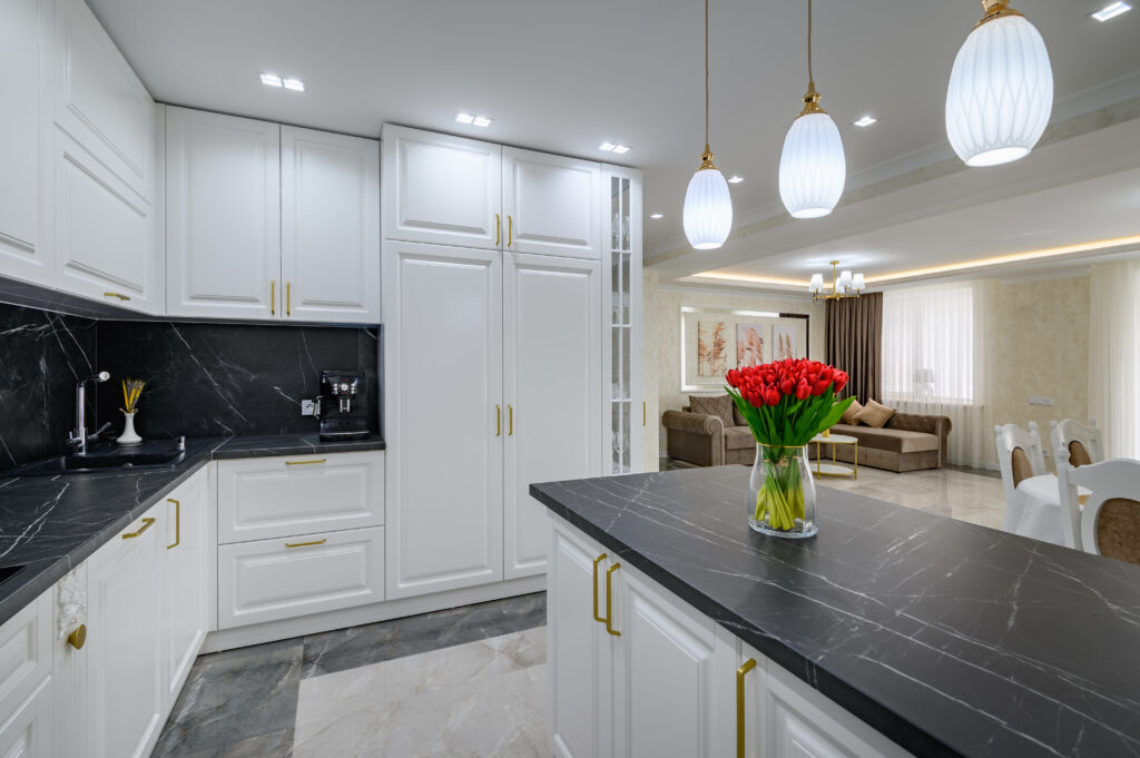 Modern white kitchen remodel with island, pendant lights, and stainless steel appliance